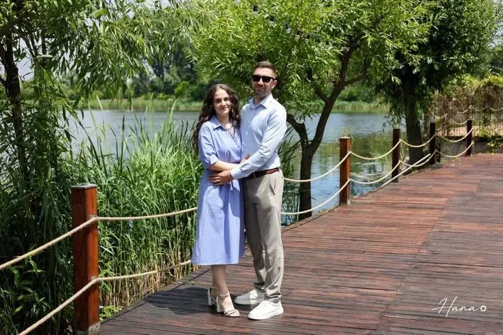 Couple walking on a wooden path by a lake